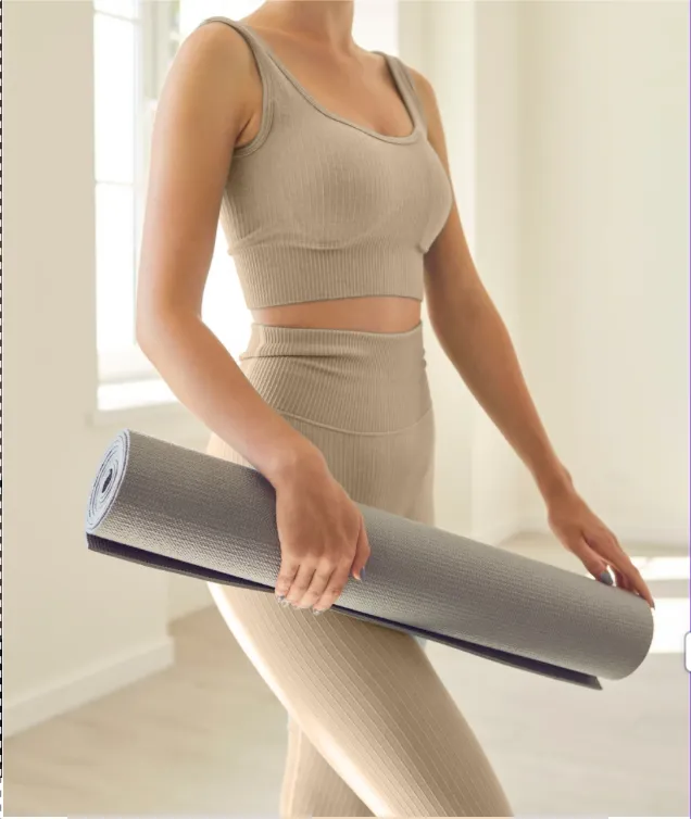 woman holding pilates mat